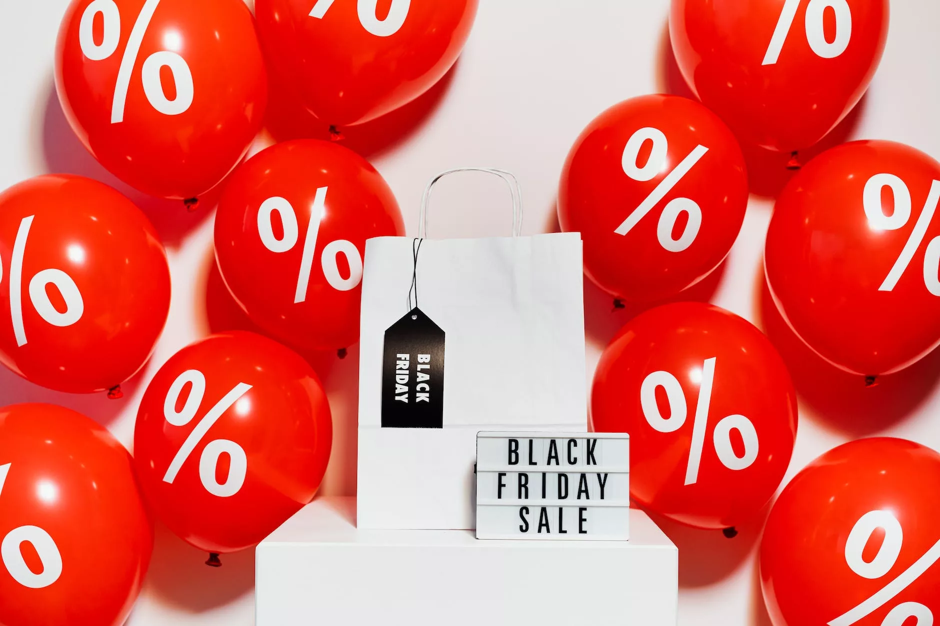 red and white balloons on white wall with black friday sale writing