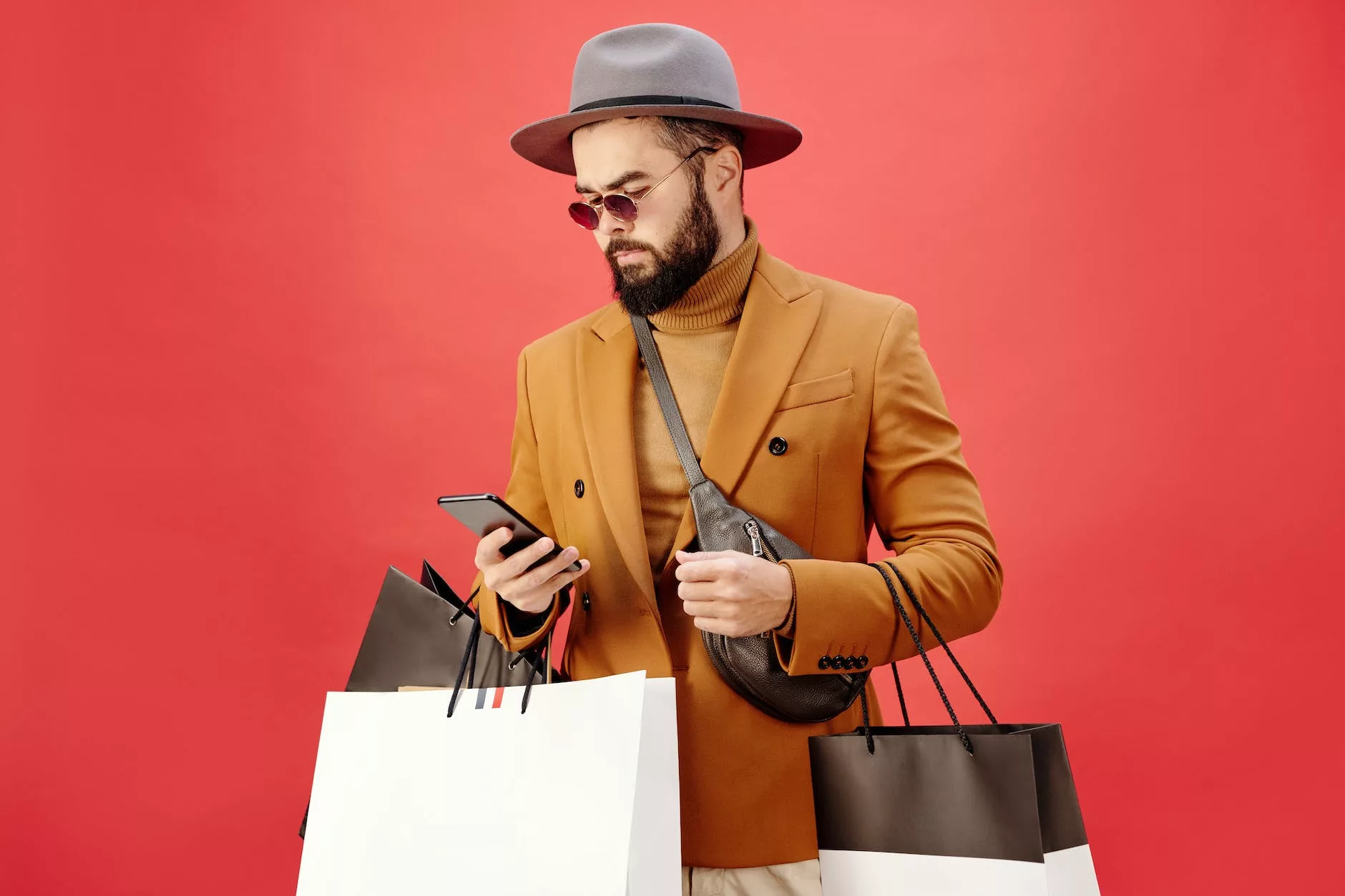 man in a brown blazer carrying shopping bags while using his cell phone in Black Friday