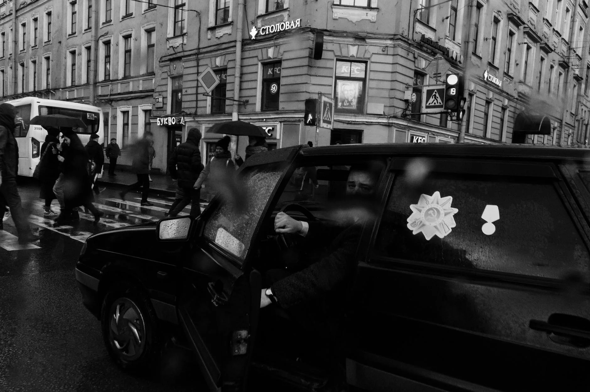 man in black car with medal stickers stopped near crosswalk